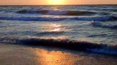 Fırtınalı deniz. Gün batımında ve şafakta denizde beyaz köpüklü büyük dalgalar. Mavi deniz, turuncu kırmızı gökyüzü. Kıyı sahili kıyı şeridi. Doğal zemin arkaplan fırtınası Yavaş çekim