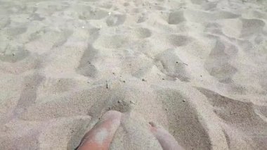 Ayakları kumda kazı yapan bir kadın. Sıcak yaz gününde kumsalda ayaklarını kuru kuma gömme oyunu oynayan biri. Tatil tatili, tatil, dinlenme, turizm...