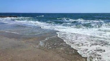 Fırtınalı deniz. Büyük deniz dalgaları güneşli yaz gününde eski beton iskeleye çarpıp çarpıyor. Beyaz köpüklü yüksek dalgalar. Büyük dalgalar kopuyor, çimento iskelesine yayılıyor. Patlamalar ve sıçramalar.