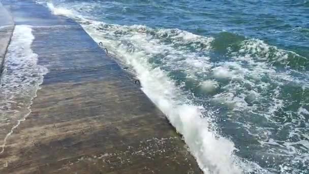 ストーミー海 大きな海の波が衝突し 晴れた夏の日に古いコンクリートの桟橋に当たります 白い泡の高い波 大きな波が壊れ セメントの桟橋に広がりました スプラッシュバーストとスプラッシュ — ストック動画