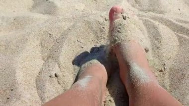 Ayakları kumda kazı yapan bir kadın. Sıcak yaz gününde kumsalda ayaklarını kuru kuma gömme oyunu oynayan biri. Tatil tatili, tatil, dinlenme, turizm...