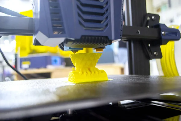 3D printer printing prototype from molten plastic. Process of creating prototype model on 3D printer from yellow melted plastic close-up. Additive new printer technology. Modern printing