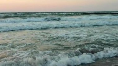 Fırtınalı deniz. Gün batımında ve şafakta denizde beyaz köpüklü büyük dalgalar. Mavi deniz, turuncu kırmızı gökyüzü ve güneş. Sahil kıyısı kıyı şeridi. Doğal arka plan doğa fırtınası