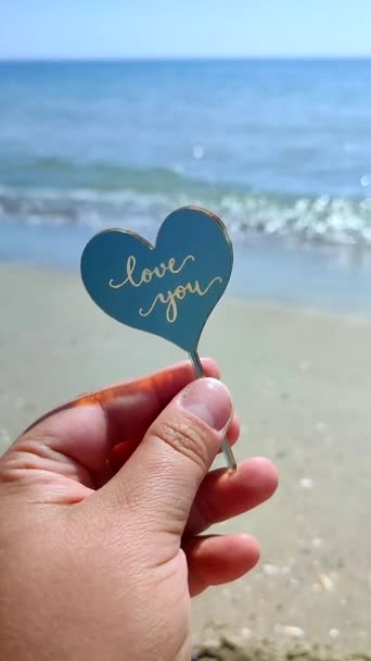 손가락 플라스틱 모양의 심장과 단어를 해변에서 해변과 파도에 당신을 로맨스 — 비디오