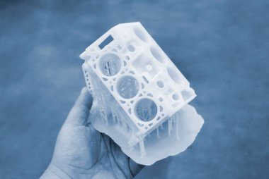 Avucunun içinde erimiş beyaz plastikten 3 boyutlu yazıcıya basılmış araba motoru prototipi tutan kişi. Üç boyutlu model. Katkı sağlayan yenilikçi modelleme teknolojisi. Modern yeni baskı endüstrisi.