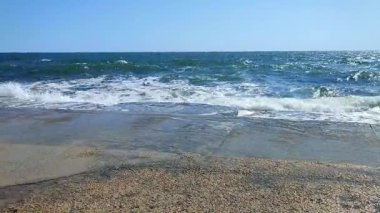 Büyük dalgalar eski çimento kıyısına çarpıyor. Güneşli bir günde dalgalar iskele iskelesine vuruyor. Fırtına, fırtınalı deniz. Hava durumu. Beyaz köpüklü yüksek dalgalar.