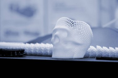 Yüzeyde erimiş beyaz plastikten küçük bir insan kafatası 3D prototipi var. Üç boyutlu model. Katkı sağlayan ilerici tıbbi teknoloji. Modern yeni baskı üretim endüstrisi.