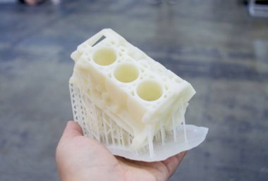 Avucunun içinde erimiş beyaz plastikten 3 boyutlu yazıcıya basılmış araba motoru prototipi tutan kişi. Üç boyutlu model. Katkı sağlayan yenilikçi modelleme teknolojisi. Modern yeni baskı endüstrisi.