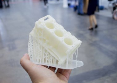 Avucunun içinde erimiş beyaz plastikten 3 boyutlu yazıcıya basılmış araba motoru prototipi tutan kişi. Üç boyutlu model. Katkı sağlayan yenilikçi modelleme teknolojisi. Modern yeni baskı endüstrisi.