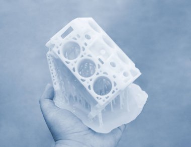 Avucunun içinde erimiş beyaz plastikten 3 boyutlu yazıcıya basılmış araba motoru prototipi tutan kişi. Üç boyutlu model. Katkı sağlayan yenilikçi modelleme teknolojisi. Modern yeni baskı endüstrisi.