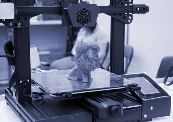 Модель игрушечного льва, напечатанная на 3D принтере из расплавленного пластика синего цвета на рабочем столе 3D принтера. Концепция 3D-принтера, 3D-печати, моделирования прототипирования трехмерного объекта. Инновационное производство