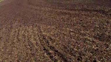 Güneşli bir günde kara toprağın üzerinde uçmak. Kazılmış bir toprak tarlası. Toprağın sürülmüş toprakları. Tarım endüstrisi tarımsal tarım arazisi. Tarım sektörü tarım işi. Hava aracı görünümü.
