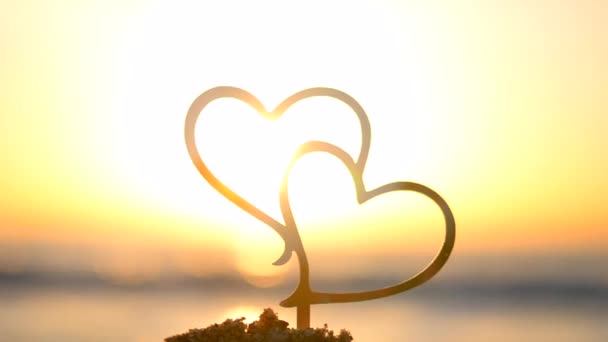 海岸の夜明けと日没に心臓の2つの黒いアウトライン 海岸に太陽が昇る背景に砂に心臓の形をした輪郭を貼ります コンセプト インフォメーション バレンタインデー — ストック動画