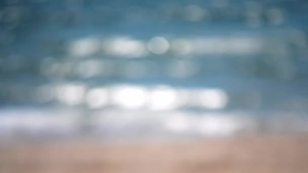 青い海の輝かしい背景 晴れた夏の日の太陽の輝きと黄色い砂浜の水に熟した白いボケのスポット 自然の背景表面水 海の川の湖の池 — ストック動画
