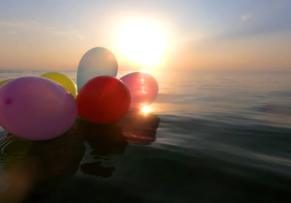 Balloons and sea. Bunch of hot air balloons floats on surface of the sea at dawn and sunset. Multi-colored air balloons on the water of the sea ocean lake pond. Relaxation entertainment romance rest