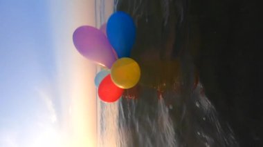 Güneşli bir yaz gününde bir grup renkli balon denizin dalgalarında salınır. Birçok renkli küçük balonlar birbirine bağlanmış olarak sabahları suyun yüzeyinde yüzerler.