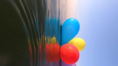 Güneşli bir yaz gününde bir grup renkli balon denizin dalgalarında salınır. Birçok renkli küçük balonlar birbirine bağlanmış olarak sabahları suyun yüzeyinde yüzerler.