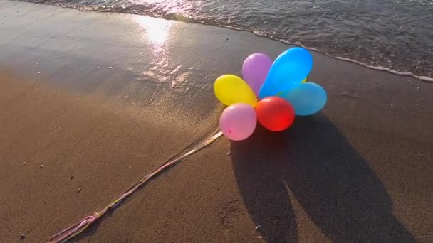 Banda Kolorowych Balonów Leżących Piasku Morskiej Plaży Falami Morskimi Słoneczny — Wideo stockowe