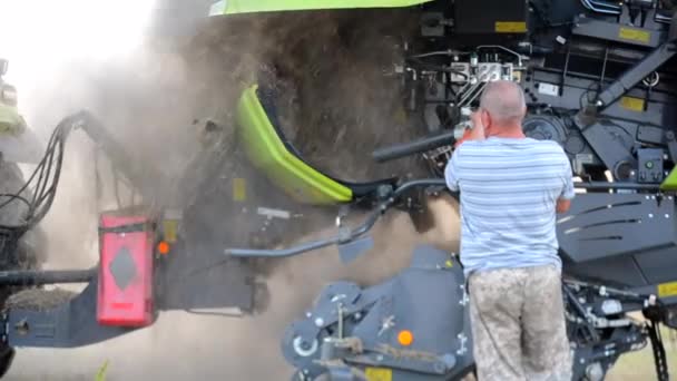 男农民在把稻草压成捆后 用泥土 稻草清洁联合拖拉机的内部 — 图库视频影像