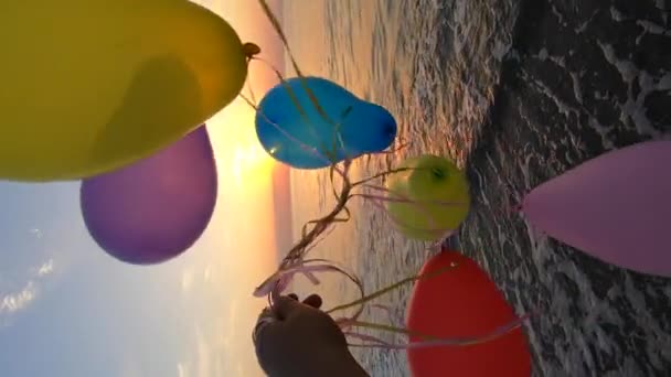 Χέρι Και Πολλά Πολύχρωμα Μπαλόνια Δεμένα Κορδέλα Στην Αμμώδη Παραλία — Αρχείο Βίντεο