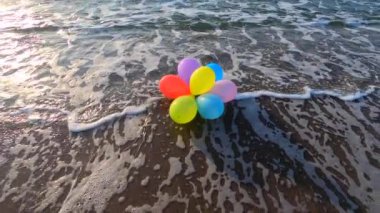 Deniz kıyısındaki kumlu sahilde, gün batımında ve sabahın köründe, deniz dalgaları üzerinde bir sürü renkli balon. Sanat yaratıcılığı