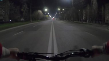 Geceleri fenerlerin ışığı altında bir adam otoyolun ortasında bisiklet sürüyor. POV