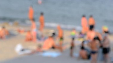 Birçok insan sıcak bir yaz gününde kumlu sahil sahillerinde dinleniyor ve denizde yüzüyor. Yazın halk plajında bir sürü beyaz tenli insan. Tatilde dinlenme aktivitesi. Bulanık arkaplan