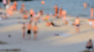 Birçok insan sıcak bir yaz gününde kumlu sahil sahillerinde dinleniyor ve denizde yüzüyor. Yazın halk plajında bir sürü beyaz tenli insan. Tatilde dinlenme aktivitesi. Bulanık arkaplan