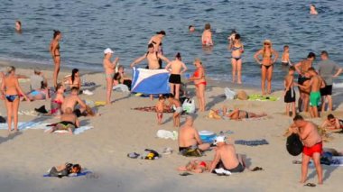Odesa, Ukrayna, 21 Ekim 2023: Birçok insan sıcak bir yaz gününde kumlu sahil sahillerinde dinleniyor ve denizde yüzüyor. Yazın halk plajında bir sürü beyaz tenli insan. Dinlenme tatili