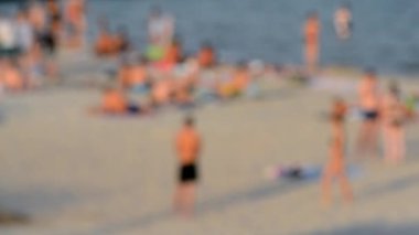 Birçok insan sıcak bir yaz gününde kumlu sahil sahillerinde dinleniyor ve denizde yüzüyor. Yazın halk plajında bir sürü beyaz tenli insan. Tatilde dinlenme aktivitesi. Bulanık arkaplan