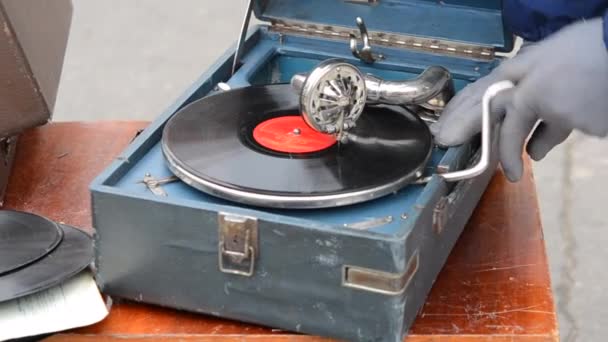 一个拿着旧留声机的手柄扭曲的人 在跳蚤市场用老式留声机播放旧的复古唱片 老式老旧的破唱片黑胶唱机 留声机 — 图库视频影像