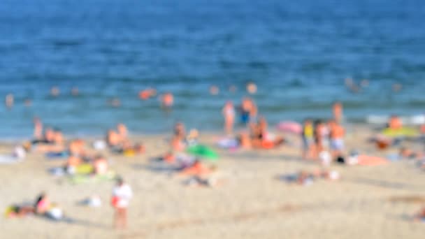 海岸の砂浜でリラックスし 暑い晴れた夏の日に海で泳ぐ多くの人々 夏には海の公共のビーチで白肌の人々がたくさんいます 休暇休暇リラックス活動 バックグラウンド — ストック動画