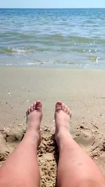ウォーマンズは晴れた夏の日に海の近くの砂浜に足を踏み入れる 海の海の波の近くの海岸の海岸の砂の上に白い肌をした女性の足 バーティカル — ストック動画