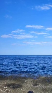 Güneşli bir günde beton setin manzarası. Mavi deniz yüzeyi, deniz dalgaları, mavi gökyüzü, beyaz bulutlar, beton yüzey. Canlı deniz manzarası var. Canlı, parlak deniz manzarası. Doğal deniz altyapısı. Dikey