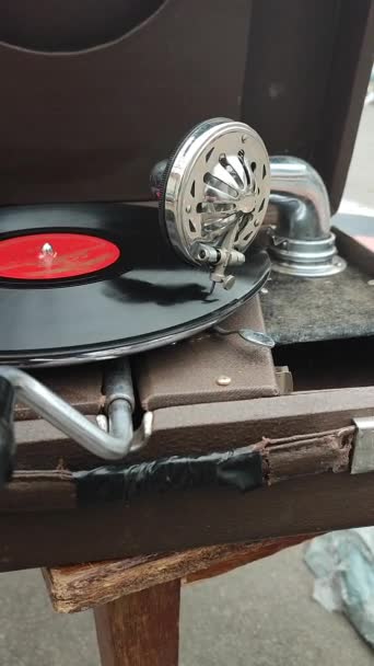 在跳蚤市场用老式留声机播放的旧唱片 便携式留声机的工作 老式破旧不堪的唱机 留声机 传声机 针尖关闭了 怀旧的古董转盘 垂直方向 — 图库视频影像