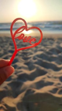 El ele tutuşan kişi el ele tutuşur kırmızı kalp ve aşk arka planda deniz ve deniz dalgaları, güneşli yaz günlerinde mavi gökyüzü. Aşk romantizmi kavramı Aziz Sevgililer Günü Dikey