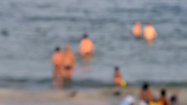 Birçok insan sıcak bir yaz gününde kumlu sahil sahillerinde dinleniyor ve denizde yüzüyor. Yazın halk plajında bir sürü beyaz tenli insan. Tatilde dinlenme aktivitesi. Bulanık arkaplan