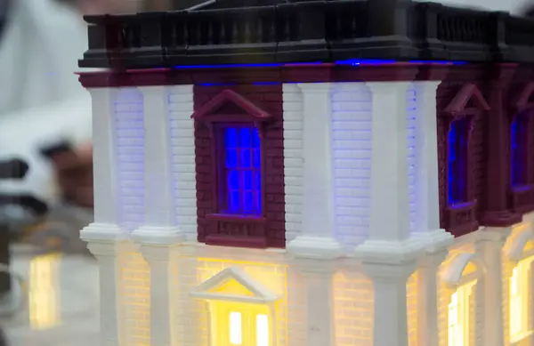 stock image Prototype printed on 3D printer brick building with columns and glowing windows. Model of building with white and brown color, windows with light shining, created by 3D printer from molten plastic