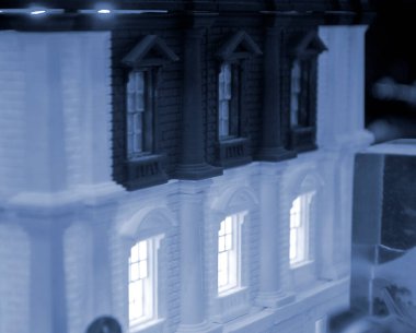 Model of building with white and black color, windows with light shining, created by 3D printer from molten plastic. Prototype printed on 3D printer brick building with columns and glowing windows. clipart