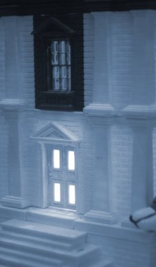 Model of building with white and black color, windows with light shining, created by 3D printer from molten plastic. Prototype printed on 3D printer brick building with columns and glowing windows. clipart