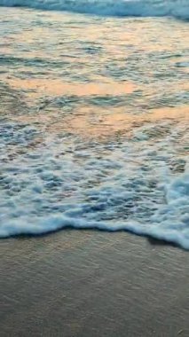 Deniz. Gün batımında ve şafakta denizde beyaz köpüklü büyük dalgalar. Mavi deniz, turuncu kırmızı gökyüzü. Sahil kıyısı kıyı şeridi. Doğal arkaplan doğa fırtına düşey
