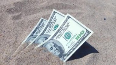 Paranın yarısı kumla kaplıydı ve sahilde yatıyordu. Paralar yere. Kumsalda kumlara gömülü dolar banknotları. Konsept finans, para, para, para, fatura, finans, kazanç, ekonomi