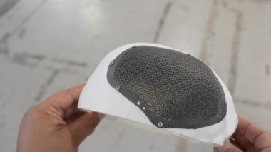 Elinde beyaz plastikten insan kafatası prototipi tutan bir adam. 3 boyutlu yazıcıda biyolojik uyumlu titanyumdan yapılmış hastalara özel bir kafatası ızgarası var. Biyomühendislik implantı