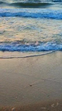 Güzel deniz dalgaları kumlu sahil sahillerinde bir yaz sabahı şafak sökerken. Güzel deniz manzarası. Deniz manzaralı deniz manzarası. Sahildeki sahil şeridi manzarası. Doğa, doğal arka plan. Dikey