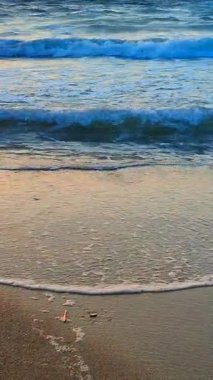 Güzel deniz dalgaları kumlu sahil sahillerinde bir yaz sabahı şafak sökerken. Güzel deniz manzarası. Deniz manzaralı deniz manzarası. Sahildeki sahil şeridi manzarası. Doğa, doğal arka plan. Dikey