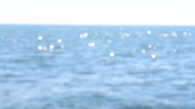 Güneşli bir yaz gününde deniz manzarası. Deniz Burnu. Mavi deniz suyu yüzeyli deniz manzarası, küçük dalgalanmalar ve güneşi yansıtan parlak lekeler. Bulanık soyut doğal arkaplan