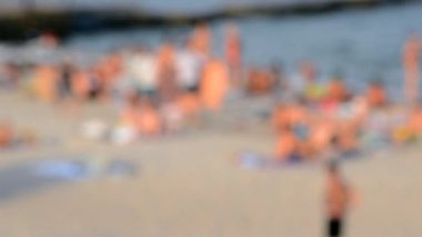 Birçok insan sıcak bir yaz gününde kumlu sahil sahillerinde dinleniyor ve denizde yüzüyor. Yazın halk plajında bir sürü beyaz tenli insan. Tatilde dinlenme aktivitesi. Bulanık arkaplan