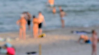 Birçok insan sıcak bir yaz gününde kumlu sahil sahillerinde dinleniyor ve denizde yüzüyor. Yazın halk plajında bir sürü beyaz tenli insan. Tatilde dinlenme aktivitesi. Bulanık arkaplan