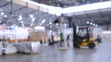 Büyük bina içinde inşaat çalışmaları. Bina enstalasyon sergi merkezi. Şantiyede yükleyici makinesi. Kurulum işinde birçok kişi çalışır. Bulanık Arka Plan