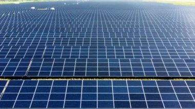 Hava aracı güneş enerjisi istasyonu panelleri üzerinde uçuyor. Güneş çiftliğinin havadan görünüşü. Yeşil enerji, elektriksel yenilik. Yenilenebilir Enerji. Güneş enerjisi üreten endüstriyel güneş enerjisi çiftliği.